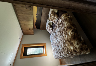 Chambre confortable dans l'Arlberg Cabin à Austriaparks Camping Arlberg, Autriche, avec placards et lit douillet.