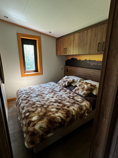Chambre de l'Arlberg Cabin à Austriaparks Camping Arlberg en Autriche, avec lit double et mobilier en bois.
