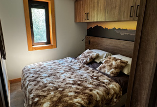 Chambre de l'Arlberg Cabin à Austriaparks Camping Arlberg en Autriche, avec lit double et mobilier en bois.