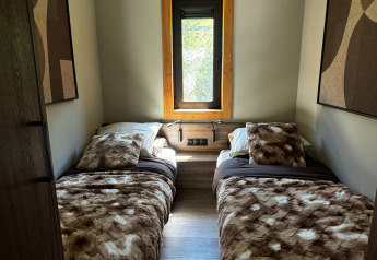 Habitación acogedora con dos camas individuales, mantas peludas y ventana en Arlberg Cabin, Austriaparks Camping Arlberg.