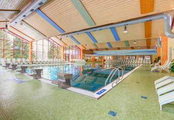 Piscina cubierta en Arlberg Cabin en Austriaparks Camping Arlberg, con tumbonas y grandes ventanales.