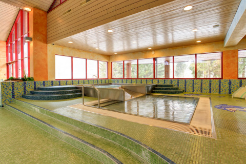 Binnenzwembad met whirlpool, mozaïektegels en grote ramen in een gezellige lodge omgeving.
