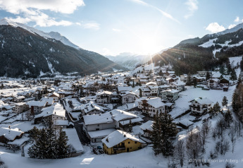 Vista invernal de la cabaña Arlberg en Austriaparks Camping Arlberg, rodeada de montañas nevadas en Austria.