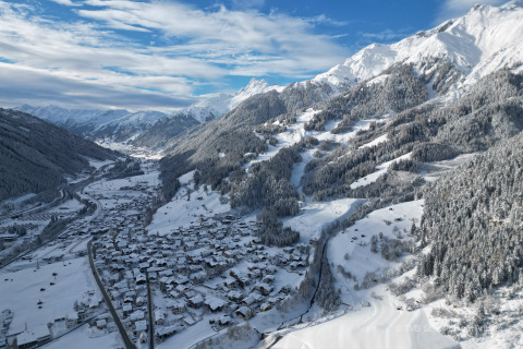 Vue sur une vallée enneigée et un village depuis Arlberg Cabin à Austriaparks Camping Arlberg en Autriche.