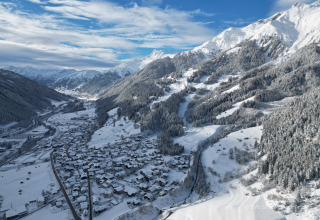 Vue sur une vallée enneigée et un village depuis Arlberg Cabin à Austriaparks Camping Arlberg en Autriche.
