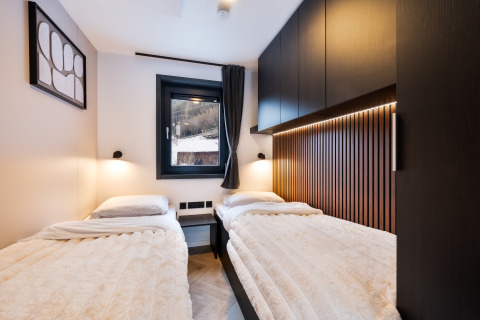 Moderne slaapkamer met twee bedden in Stanzertal Cabin, Austriaparks Camping Arlberg, Oostenrijk, houten accenten.