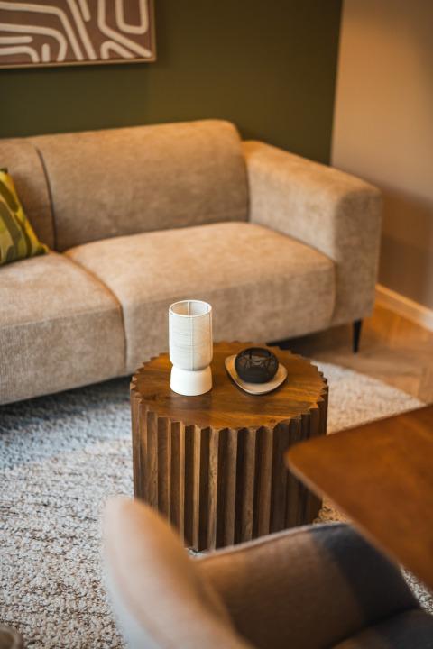 Gezellige loungeruimte in een lodge met beige bank, houten tafeltje en moderne decoratie op vloerkleed.