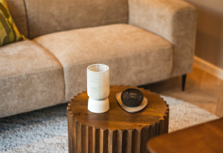 Gezellige loungeruimte in een lodge met beige bank, houten tafeltje en moderne decoratie op vloerkleed.