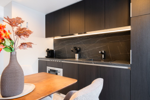 Moderne køkken i en lodge med mørke skabe, marmor bordplade, og spisebord med blomsterdekoration.