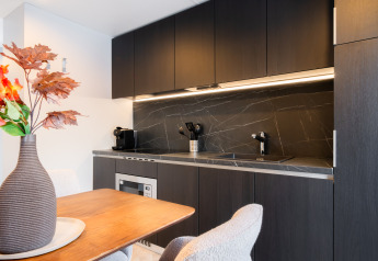 Cocina moderna de lodge con armarios oscuros, encimera de mármol y mesa de comedor con jarrón.