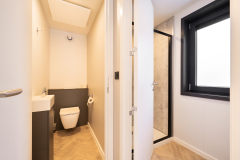 Badkamer in een lodge met apart toilet en douche, groot raam en moderne houten vloer.