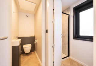 Badkamer in een lodge met apart toilet en douche, groot raam en moderne houten vloer.