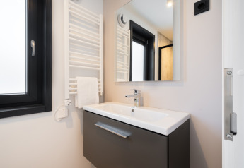Baño moderno de lodge con lavabo, espejo, calentador de toallas y ventana de marco negro.