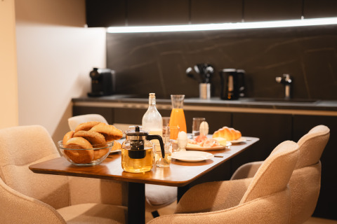 Gezellige ontbijttafel in een lodge met vers brood, sap, thee en eieren in een moderne keukenruimte.