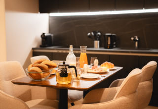 Gezellige ontbijttafel in een lodge met vers brood, sap, thee en eieren in een moderne keukenruimte.