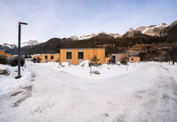 Cabañas modernas de madera en un complejo invernal rodeado de nieve y montañas al fondo.