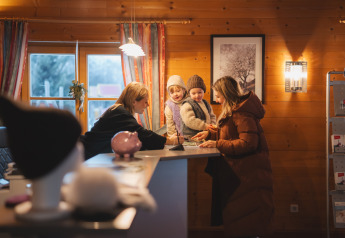 Famille à la réception d’un chalet en bois chaleureux, aidée par le personnel durant la saison hivernale.