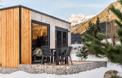 Cabane Stanzertal à Austriaparks Camping Arlberg, Autriche. Lodge moderne et neige, montagnes derrière.