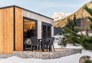 Stanzertal Cabin ved Austriaparks Camping Arlberg i sneklædte østrigske bjerge, terrasse og stole.