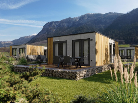 Moderne Stanzertal-hytte ved Austriaparks Camping Arlberg, omgivet af bjerge og grønne plæner i Østrig.
