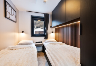 Moderne hytte-soveværelse med to enkeltsenge, trægulv og hyggelig belysning på Stanzertal Cabin i Østrig.