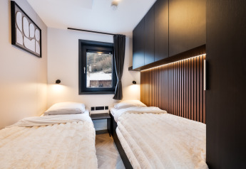 Chambre moderne avec deux lits simples, décor bois et éclairage doux au Stanzertal Cabin, Autriche.