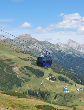 Télécabine survolant les Alpes autrichiennes près de Stanzertal Cabin, avec collines vertes et ciel bleu.
