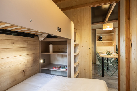 Indvendigt billede af Mobile Home Vancouver hos Huttopia Divonne Les Bains med køjesenge og spisebord.