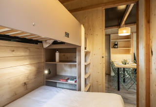 Indvendigt billede af Mobile Home Vancouver hos Huttopia Divonne Les Bains med køjesenge og spisebord.