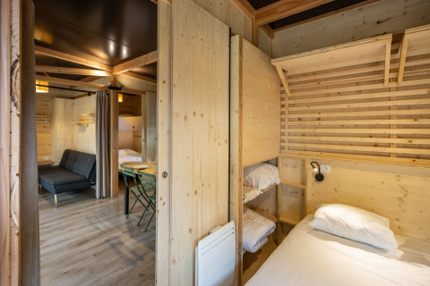 Interiør af Mobile Home Vancouver på Huttopia Divonne Les Bains med træpaneler og køjesenge.