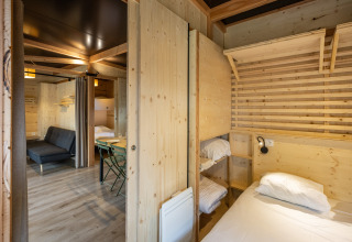 Interiør af Mobile Home Vancouver på Huttopia Divonne Les Bains med træpaneler og køjesenge.