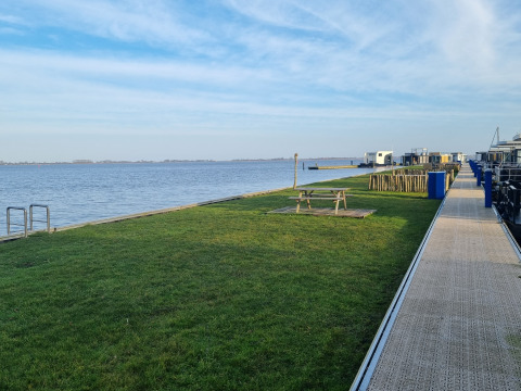 Vue sur le lac près de la Houseboat Aqua Dolce à Welcome In Friesland, Pays-Bas, pelouse et banc pique-nique.