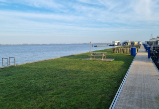 Vista lago dalla Houseboat Aqua Dolce a Welcome In Friesland, Paesi Bassi, con prato e tavolo da picnic.