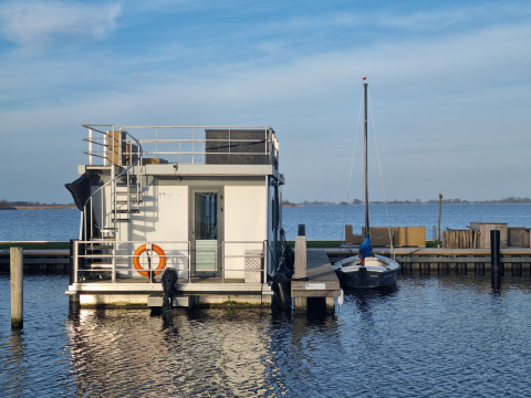Casa flotante Houseboat Aqua Dolce atracada en Welcome In - Friesland, Países Bajos, junto a un velero.