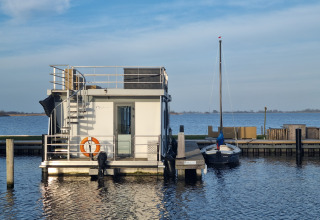 Casa flotante Houseboat Aqua Dolce atracada en Welcome In - Friesland, Países Bajos, junto a un velero.