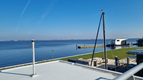 Vista dalla casa galleggiante Aqua Dolce al Welcome In - Friesland, Paesi Bassi, con cielo e lago sereno.