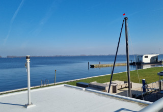 Vista desde la casa flotante Aqua Dolce en Welcome In - Friesland, Países Bajos, con cielo azul y agua tranquila.