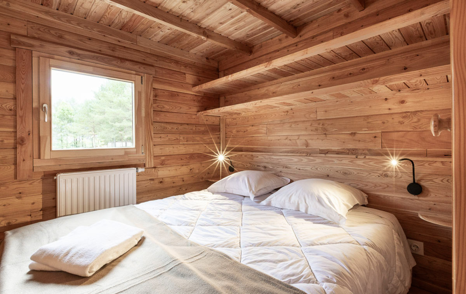 Sfeervolle slaapkamer in Chalet Montana Vista bij Huttopia Champagny en Vanoise in Frankrijk, met houten interieur.