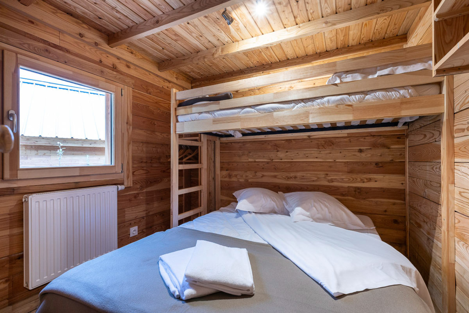Knusse slaapkamer met stapelbed en tweepersoonsbed in Chalet Montana Vista, Huttopia Champagny en Vanoise, Frankrijk.