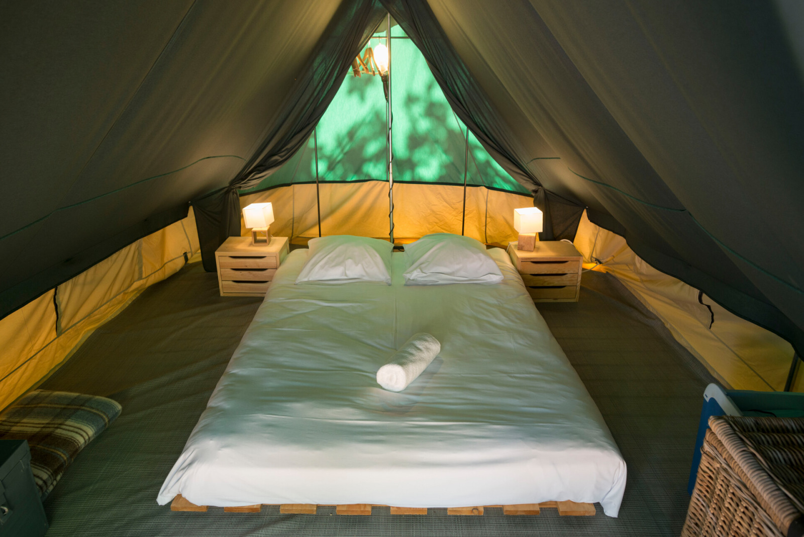 Interieur van een safaritent met tweepersoonsbed, nachtkastjes en lampen bij Tent Bonaventure, Huttopia Champagny en Vanoise.