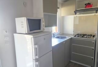 Cucina compatta della Mobile home «Royal» al Centro Vacanze San Marino con frigo, microonde e fornello a gas.