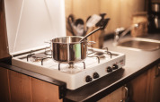Una pentola con cucchiaio su un fornello a gas nella cucina della Safari tent all’Emmerbølle Strand Camping, Danimarca.