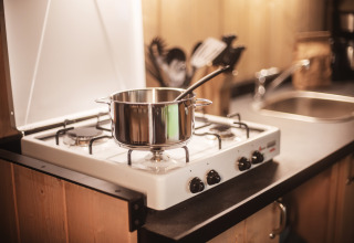 Una pentola con cucchiaio su un fornello a gas nella cucina della Safari tent all’Emmerbølle Strand Camping, Danimarca.