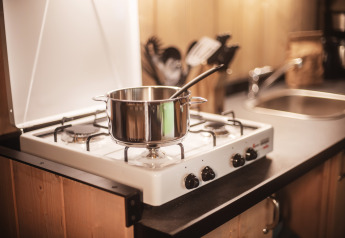 Una pentola con cucchiaio su un fornello a gas nella cucina della Safari tent all’Emmerbølle Strand Camping, Danimarca.