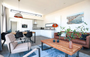 Moderne woonkamer en keuken in een tiny house bij EuroParcs Bad Meersee met lederen zetel.