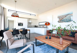 Moderne woonkamer en keuken in een tiny house bij EuroParcs Bad Meersee met leren bank.