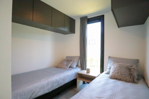 Moderne slaapkamer met twee eenpersoonsbedden in tiny house Cube Exclusive Plus bij EuroParcs Bad Meersee.