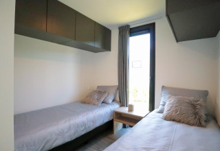 Moderne slaapkamer met twee eenpersoonsbedden in tiny house Cube Exclusive Plus bij EuroParcs Bad Meersee.