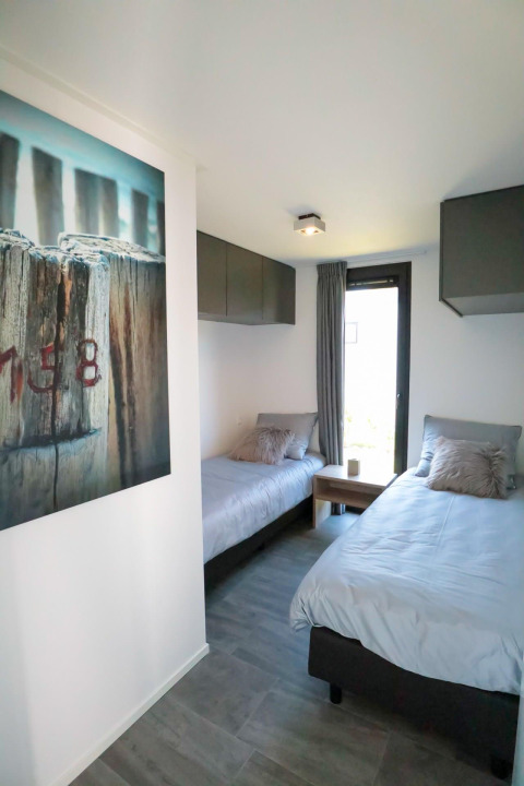 Modern bedroom with two single beds in a tiny house at EuroParcs Bad Meersee, Netherlands.