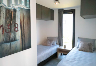 Modern bedroom with two single beds in a tiny house at EuroParcs Bad Meersee, Netherlands.